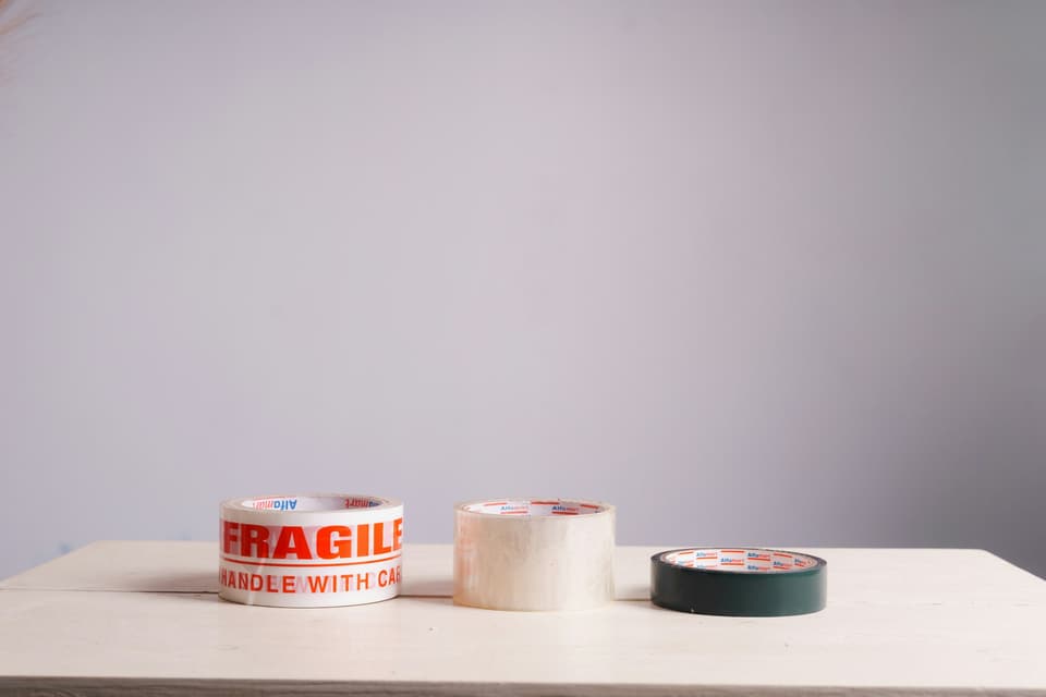 Rolls of packing tape, one printed FRAGILE, on a table