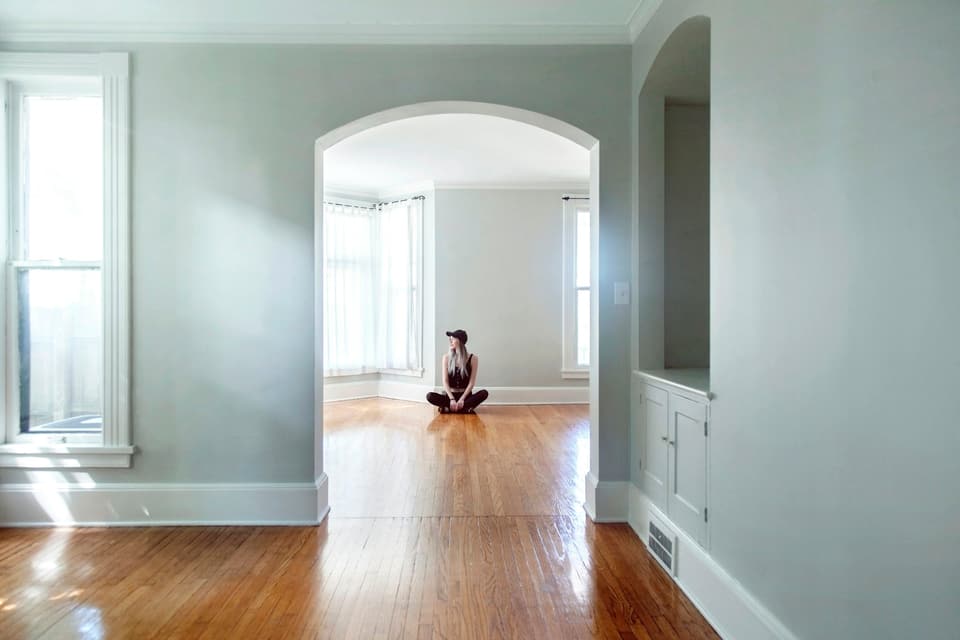 A person sitting on the floor of an empty, freshly painted room